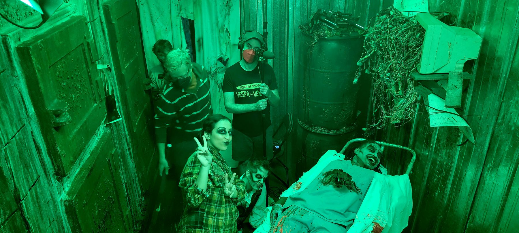 Cast and crew smiling between takes inside one of Realm of Terror's green-lit scenes.
