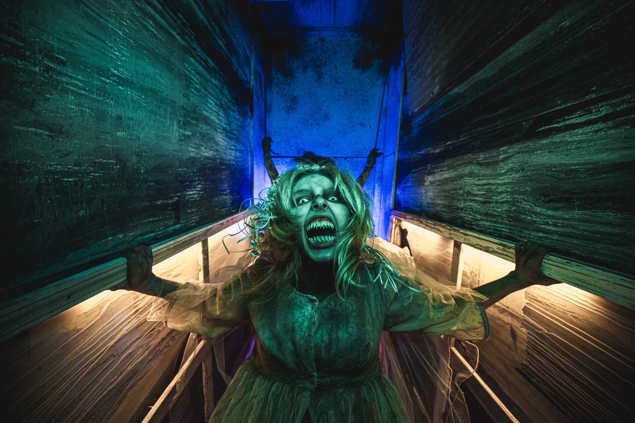 Live creature actor performing in a narrow green-lit Realm of Terror hallway